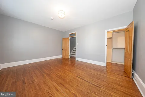 a view of empty room with wooden floor and fan