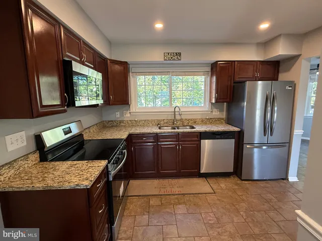 a kitchen with granite countertop a sink a counter top stainless steel appliances and cabinets