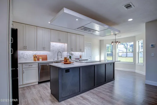 a kitchen with kitchen island granite countertop a sink cabinets and wooden floor