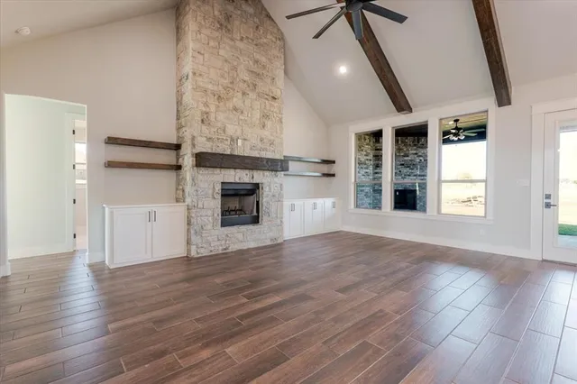 an empty room with wooden floor fireplace and windows