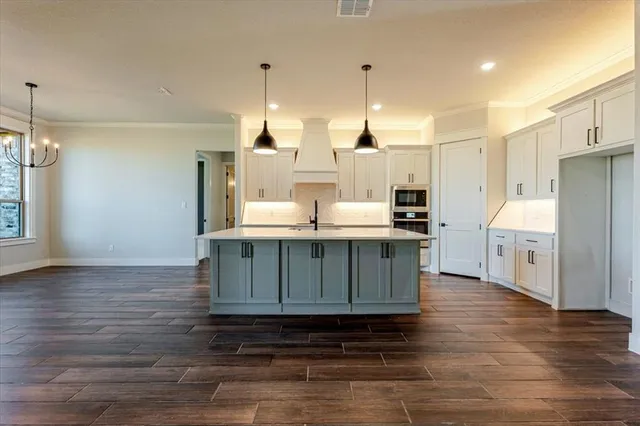 a kitchen with stainless steel appliances kitchen island granite countertop a sink a stove and a wooden floors