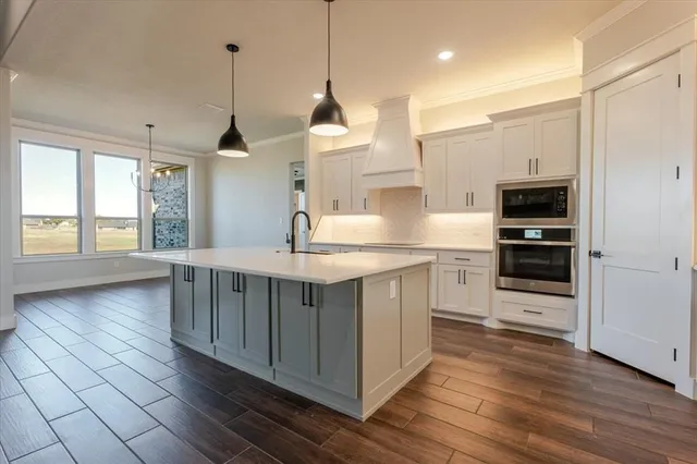 a kitchen with stainless steel appliances granite countertop a stove a sink and a wooden floors