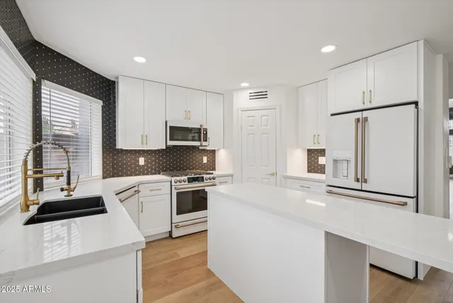 a kitchen with white cabinets and stainless steel appliances