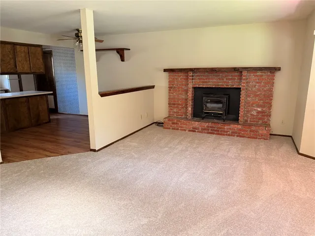 an empty room with wooden floor a fireplace and window