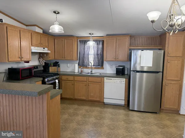 a kitchen with a refrigerator a sink dishwasher a oven with white cabinets and wooden floor