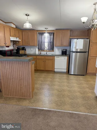 a kitchen with granite countertop a refrigerator a sink a stove a microwave and cabinets