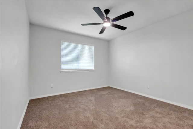 an empty room with a ceiling fan and window