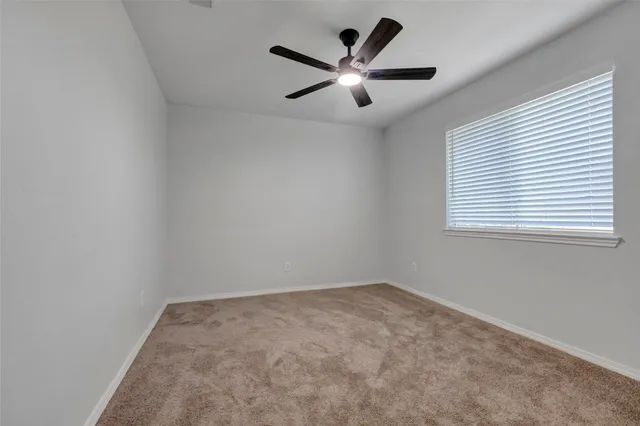 an empty room with ceiling fan and windows