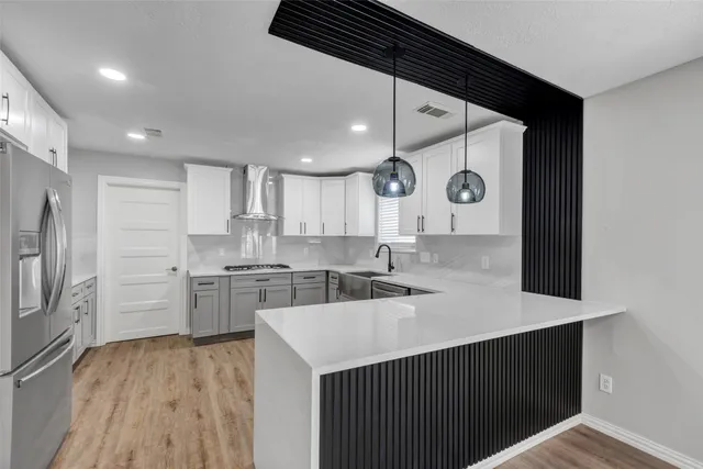 a kitchen with a refrigerator a sink and dishwasher with wooden floor