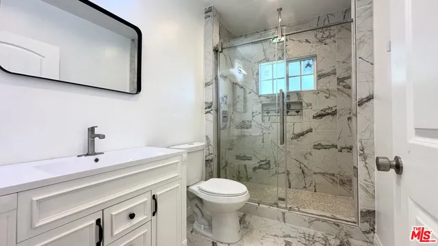 a bathroom with a sink a toilet and shower