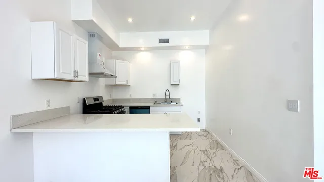 a kitchen with granite countertop a sink and white cabinets