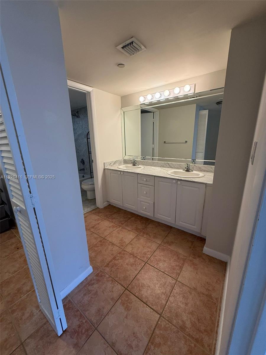 8911 Collins Avenue, Unit 1103 Surfside, FL 33154 - Photo 11 of 19 a bathroom with a sink a mirror and a bathtub