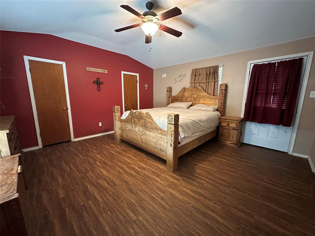 6551 Crooked Creek Road Bowie, TX 76230 - Photo 21 of 39 a bedroom with a bed lamp and wooden floor