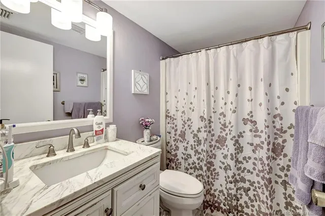 a bathroom with a granite countertop sink a toilet and a mirror
