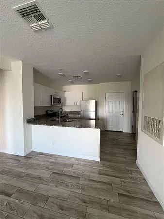 a view of kitchen and empty room with wooden floor