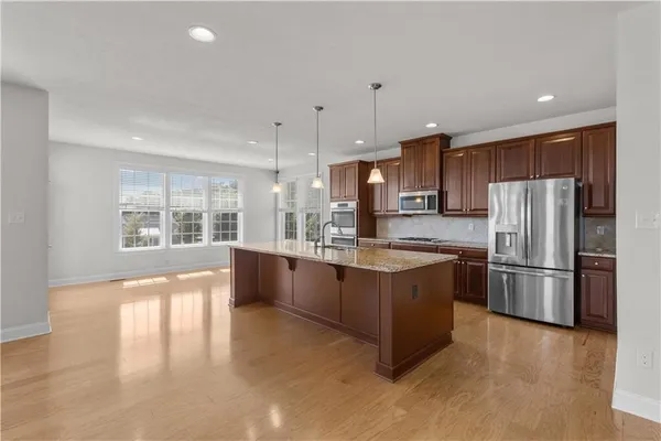 a large kitchen with stainless steel appliances granite countertop a refrigerator a sink a stove and a wooden floors
