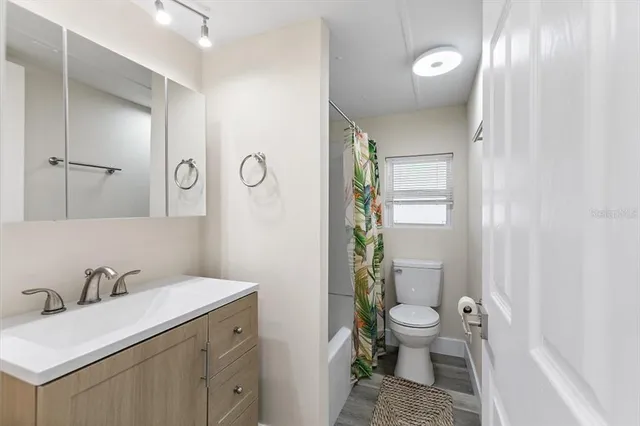 a bathroom with a granite countertop sink a toilet and shower