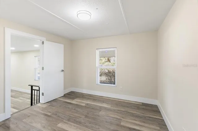 an empty room with wooden floor and windows