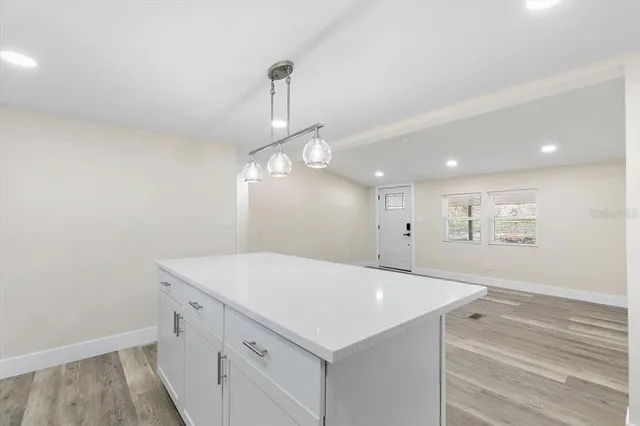 a room with a chandelier fan and wooden floor