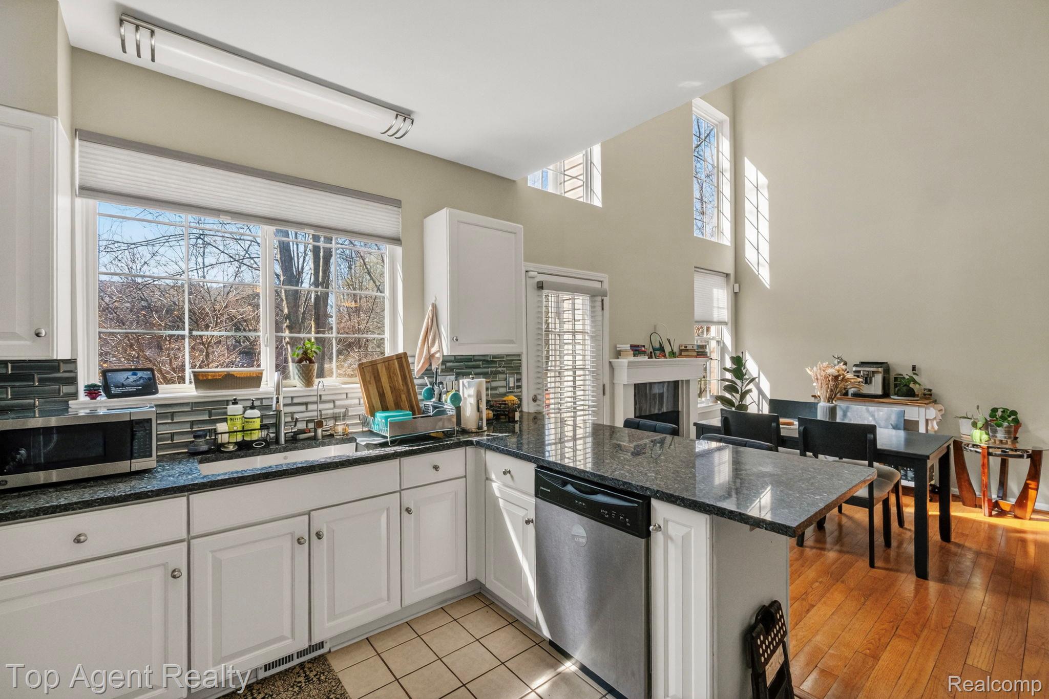 41567 Glade Road, Unit 20 Canton, MI 48187 - Photo 17 of 47 Kitchen featuring a peninsula, dark stone countertops, stainless steel appliances, white cabinets, and a high ceiling