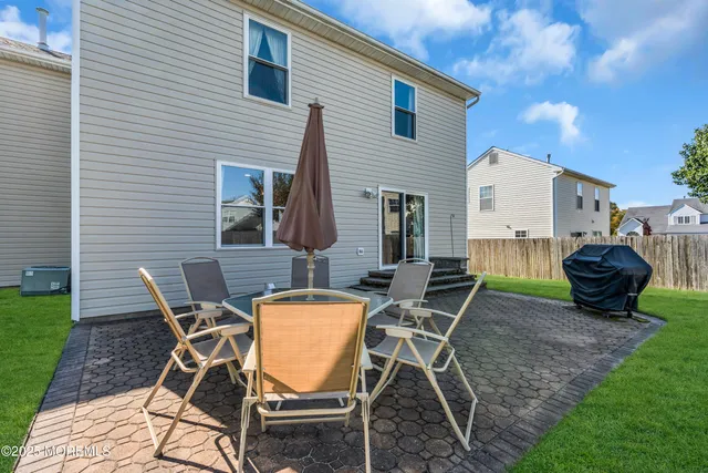 a view of a backyard with table and chairs and a barbeque with potted plants