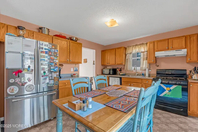 a view of a dining room with furniture one side kitchen view and wooden floor