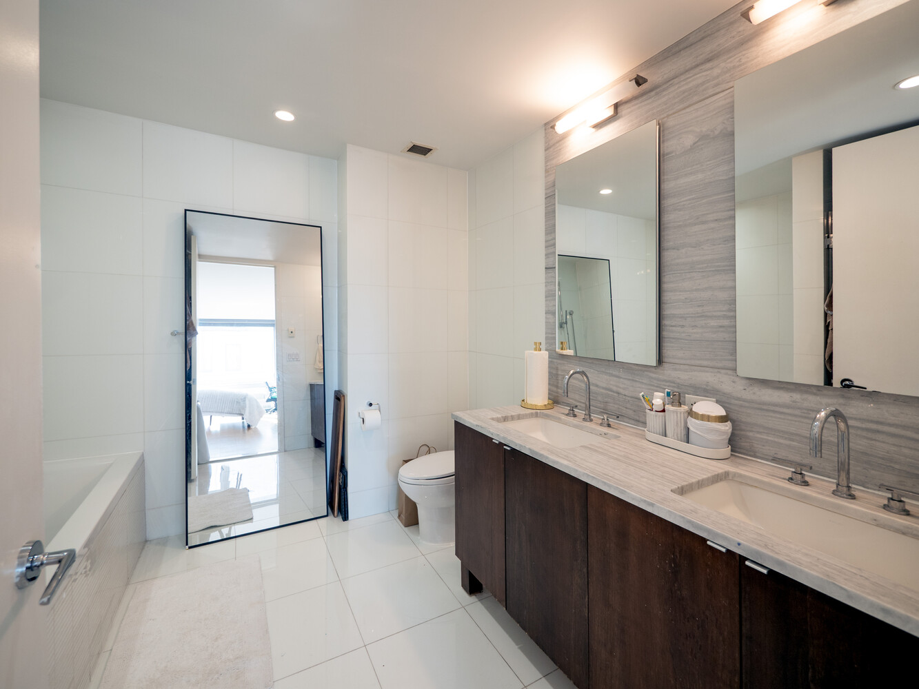 117 West 123rd Street, Unit 5D Manhattan, NY 10027 - Photo 4 of 11 a spacious bathroom with a double vanity sink a mirror and a toilet