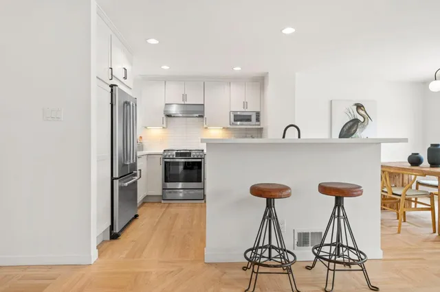 a kitchen with stainless steel appliances kitchen island a refrigerator and a stove top oven with wooden floor