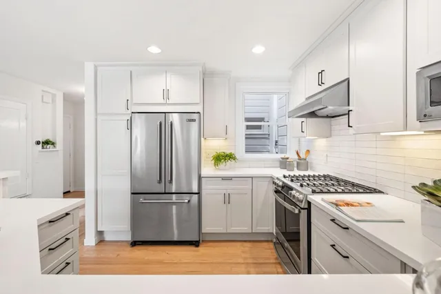 a kitchen with white cabinets and stainless steel appliances