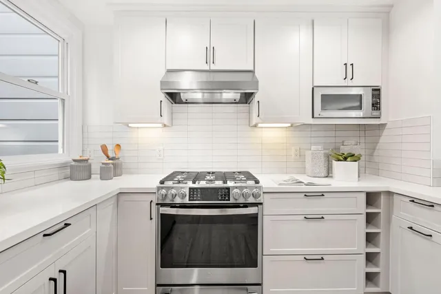a kitchen with white cabinets stainless steel appliances and sink
