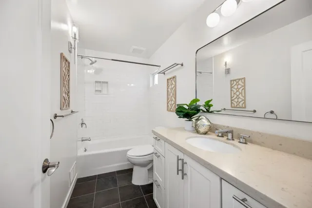 a bathroom with a granite countertop sink toilet a large mirror a shower and a bathtub