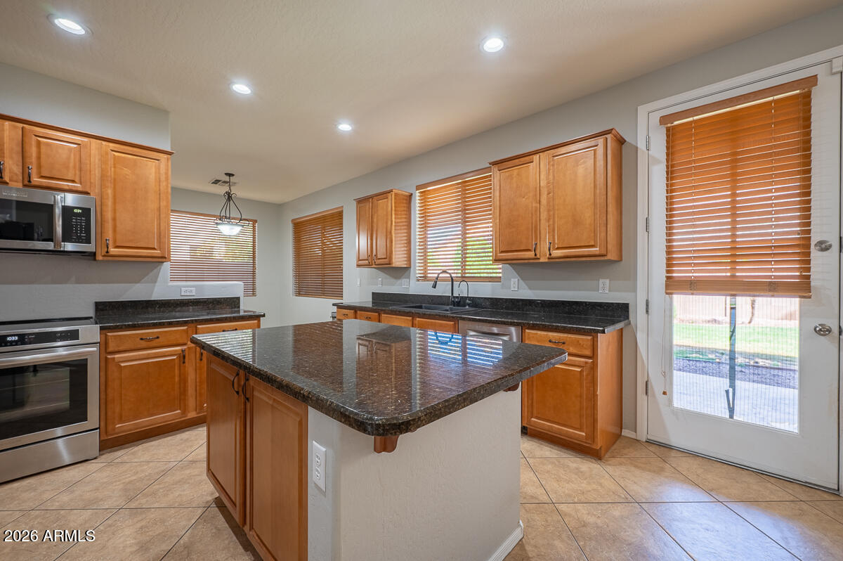 3328 East Merlot Street Gilbert, AZ 85298 - Photo 12 of 48 a kitchen with stainless steel appliances granite countertop sink stove top oven and cabinets