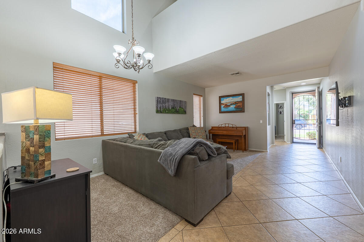 3328 East Merlot Street Gilbert, AZ 85298 - Photo 4 of 48 a living room with couches a chandelier and a dining table with wooden floor