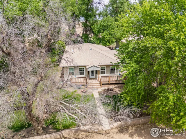 an aerial view of a house with yard and trees in the background