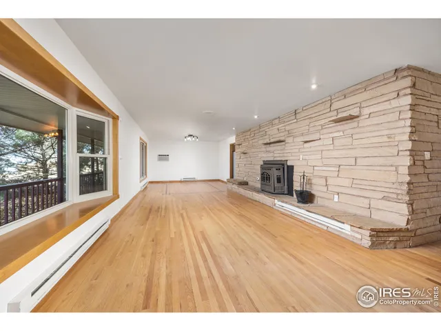 a view of empty room with wooden floor and fireplace