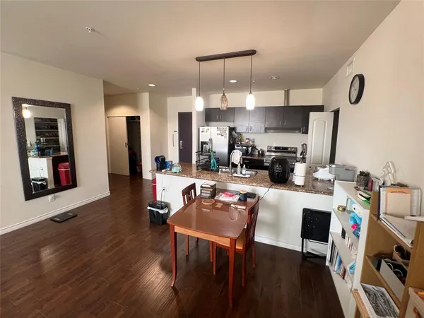 a living room with stainless steel appliances kitchen island granite countertop furniture and a wooden floor