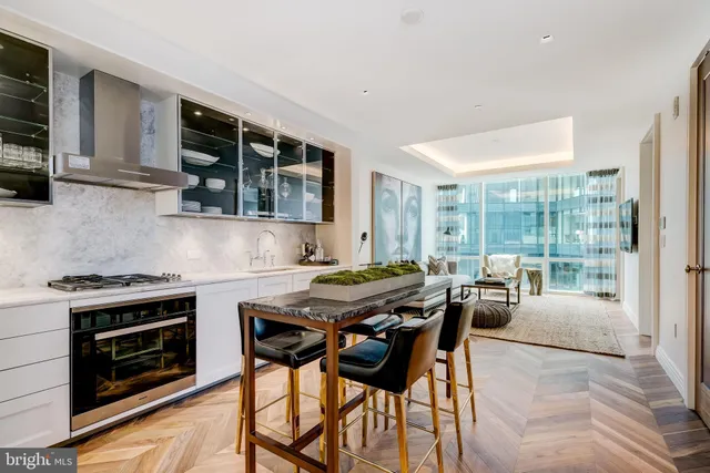 a kitchen with stainless steel appliances granite countertop a stove a sink dishwasher a microwave oven and a dining table with wooden cabinet