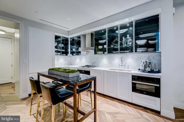 a kitchen with a stove and white cabinets with wooden floor