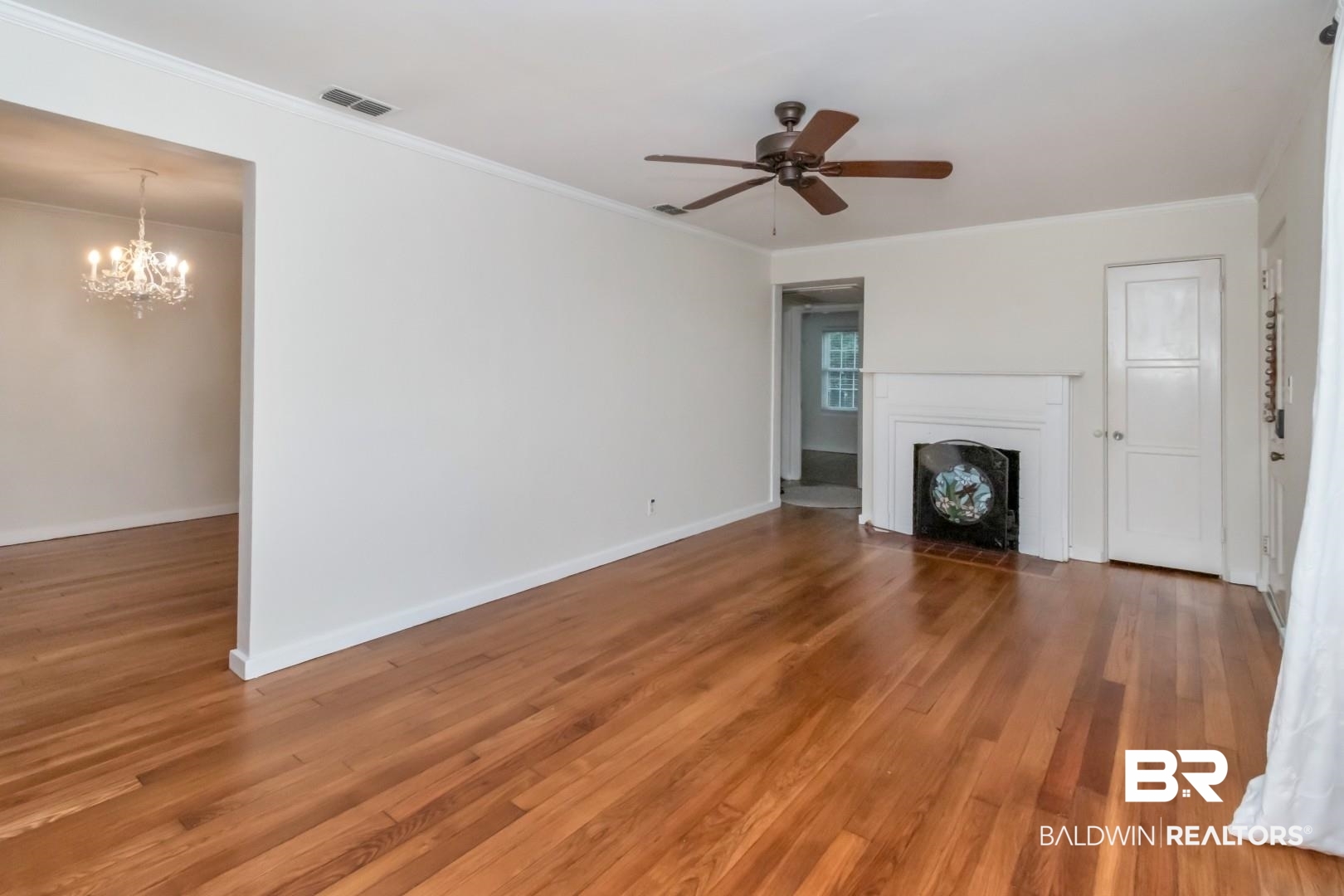 33 Lancaster Road Mobile, AL 36608 - Photo 3 of 40 Unfurnished living room with a fireplace with flush hearth, a chandelier, light wood-style floors, a ceiling fan, and ornamental molding