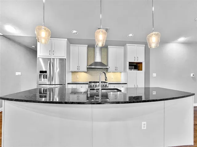 a kitchen with stainless steel appliances granite countertop a sink a refrigerator and a stove