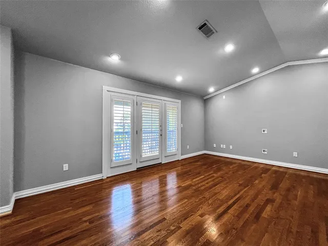 a view of an empty room with wooden floor and sliding window
