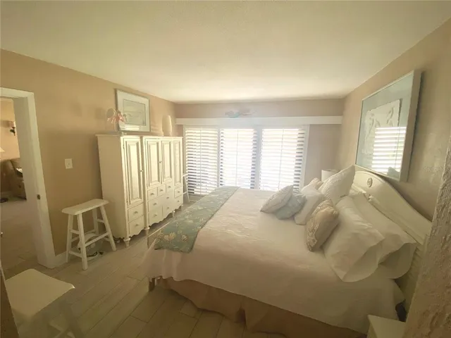 a large bed sitting in a bedroom next to a window and a chair