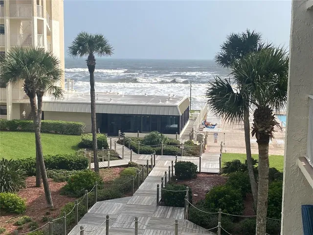 a front view of a house with a garden and lake view