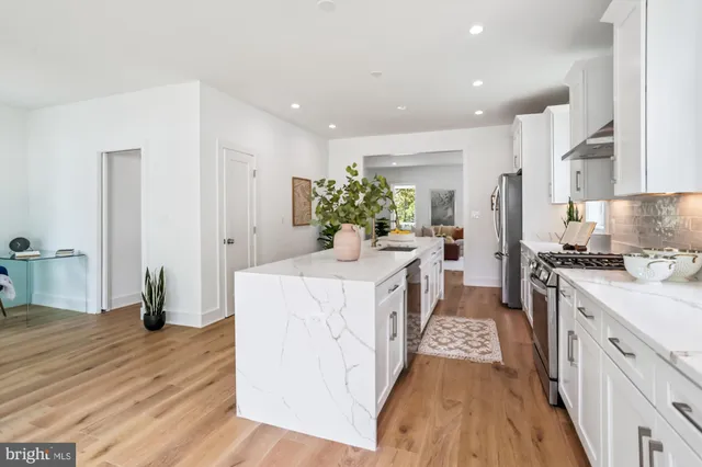 a kitchen with stainless steel appliances a white stove top oven a chimney wooden floor and cabinets