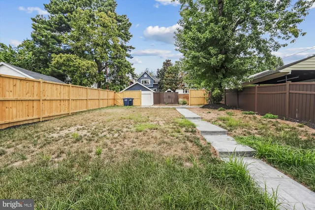 a backyard of a house with large trees and plants