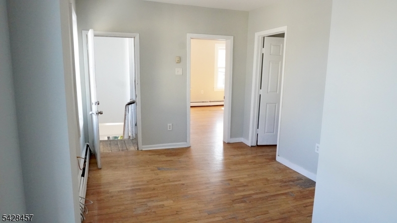 1007 Julia Street Elizabeth, NJ 07201 - Photo 9 of 20 a view of a hallway with wooden floor and a bathroom