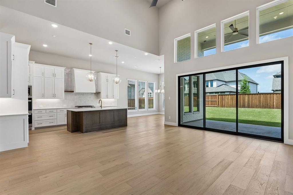 4512 Meander Way Prosper, TX 75078 - Photo 5 of 40 a large white kitchen with kitchen island and a large window