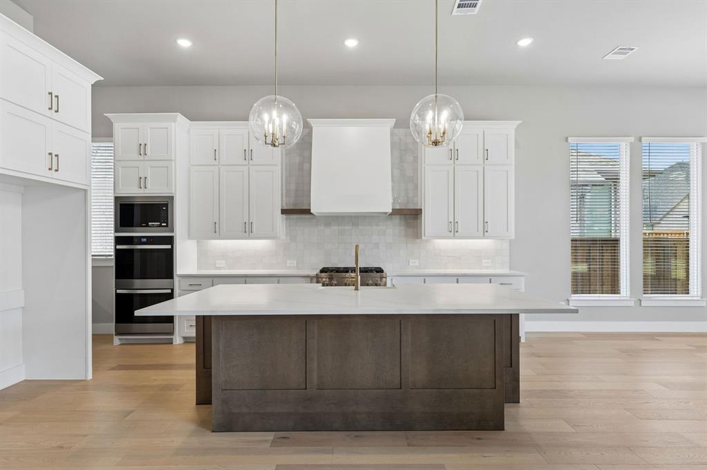 4512 Meander Way Prosper, TX 75078 - Photo 6 of 40 a large kitchen with granite countertop a large counter top a sink stainless steel appliances and cabinets