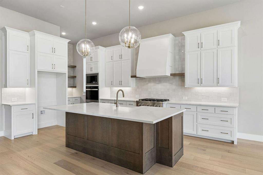 4512 Meander Way Prosper, TX 75078 - Photo 7 of 40 a large kitchen with stainless steel appliances a large center island attached withe living room