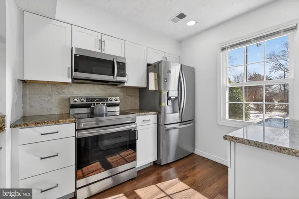 a kitchen with stainless steel appliances white cabinets a stove a microwave and a refrigerator